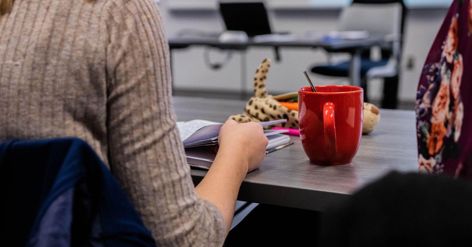 student in class with red coffee mug